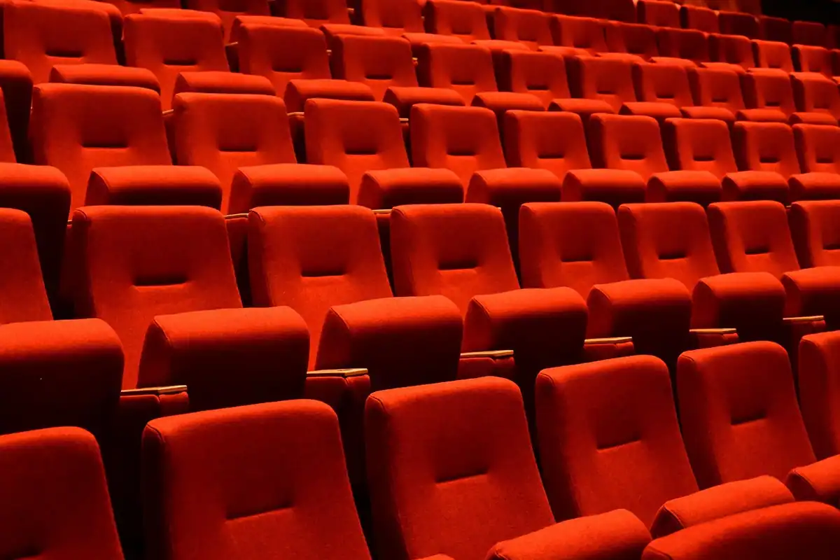 Rânduri de scaune roșii într-o sală de cinema goală, văzute de aproape