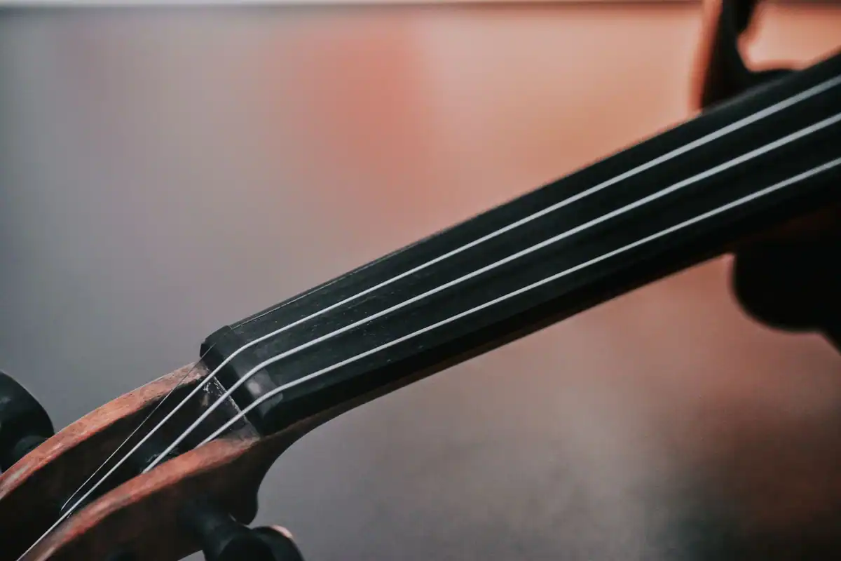 Corzile și gâtul unui violoncel, văzute de aproape, pe un fundal întunecat