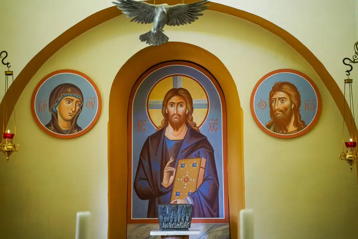 Icoane pictate în culori vii pe un perete, într-o biserică ortodoxă luminată