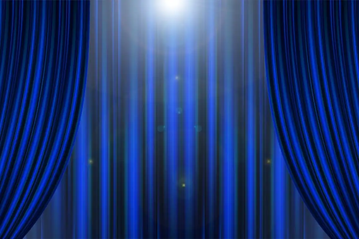 Cortină albastră de scenă, deschisă la mijloc, luminată de un reflector